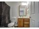 Cozy bathroom with wood vanity, neutral walls, and a shower with a polka dot curtain at 646 W Grove Cir, Mesa, AZ 85210