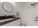 Modern bathroom features black granite countertop, round mirror, and a shower over a bathtub at 7006 E Jensen St # 40, Mesa, AZ 85207