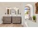 Bright bathroom featuring double sink vanity, arched window above the soaking tub, and neutral color palette at 7315 E Arlington Rd, Scottsdale, AZ 85250
