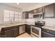 Well-equipped kitchen featuring stainless steel appliances, granite countertops, and dark wood cabinets at 7709 W Tonto Dr, Glendale, AZ 85308