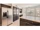 Open kitchen with a stainless steel refrigerator, dark cabinetry, granite countertops, and a dining area with windows at 7709 W Tonto Dr, Glendale, AZ 85308