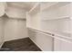 Walk-in closet featuring dark wood floors, custom shelving, and ample storage space at 7709 W Tonto Dr, Glendale, AZ 85308