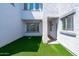 Private backyard featuring artificial turf, white walls, and manicured desert landscaping at 9110 W Palm Ln, Phoenix, AZ 85037