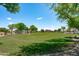 A community common area features a large grassy field and mature trees in a well-maintained park-like setting at 9110 W Palm Ln, Phoenix, AZ 85037