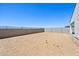 View of a large backyard with block fencing, desert landscaping, and a white stucco home at 9547 W Parkway Dr, Tolleson, AZ 85353
