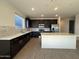 Open-concept kitchen with stainless steel appliances, dark cabinets, and a large island at 9547 W Parkway Dr, Tolleson, AZ 85353