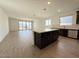 Open-concept living space with a kitchen island, tile flooring, and large sliding glass doors to the patio at 9547 W Parkway Dr, Tolleson, AZ 85353