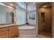 Bathroom featuring a soaking tub with stone surround, large window, and a walk-in shower at 11651 E Appaloosa Pl, Scottsdale, AZ 85259