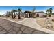 Single-story home with black trim, palm trees, desert landscape, and cracked asphalt street at 12805 W Colter St, Litchfield Park, AZ 85340