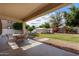 Relaxing covered patio overlooks a spacious backyard with lush green grass and a storage shed at 15028 W Minnezona Ave, Goodyear, AZ 85395