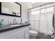 Bathroom showcasing a stylish vanity with a black countertop, white cabinets, and tiled walls at 15028 W Minnezona Ave, Goodyear, AZ 85395