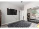 Bedroom with large TV, mirrored closet, neutral walls, and a comfortable bed with patterned bedding at 15028 W Minnezona Ave, Goodyear, AZ 85395