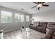Living room filled with natural light with a ceiling fan, neutral walls, and wood flooring at 15028 W Minnezona Ave, Goodyear, AZ 85395
