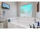 Bathroom soaking tub and frosted window featuring a television, candle and decorative accents at 15849 W Alvarado Dr, Goodyear, AZ 85395