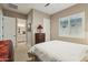Comfortable bedroom with neutral tones, a shuttered window, and an ensuite bathroom access at 15849 W Alvarado Dr, Goodyear, AZ 85395