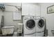 Bright laundry room features modern washer and dryer with ample white cabinet storage and convenient hanging rack at 15849 W Alvarado Dr, Goodyear, AZ 85395