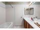 Bathroom with a white tiled shower and tub, vanity and sink, and updated lighting at 17912 N 88Th Dr, Peoria, AZ 85382