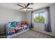 A vibrant bedroom with daybed, carpet, ceiling fan, and a view to trees from the window at 1887 W Desert Seasons Dr, Queen Creek, AZ 85144