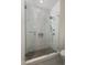 Modern shower with frameless glass doors, white subway tile walls, and gray hexagonal floor tiles at 22406 N 36Th Way, Phoenix, AZ 85050