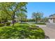Beautifully landscaped backyard with a sparkling pool, green grass, mature trees, and a pergola at 23902 S 202Nd Ct, Queen Creek, AZ 85142