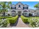 Elegant two-story home featuring a well-manicured lawn, lush greenery, and a charming brick pathway to the front door at 23902 S 202Nd Ct, Queen Creek, AZ 85142