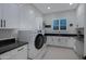 Bright laundry room with white cabinets, dark countertop, a sink and a window at 23902 S 202Nd Ct, Queen Creek, AZ 85142