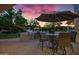 Outdoor kitchen with built-in grill, bar seating, dining table, and a relaxing ambiance under the evening sky at 23902 S 202Nd Ct, Queen Creek, AZ 85142