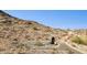 A hillside with a stone wall feature overlooks a desert landscape with a desert path at 3367 N Highlands Dr # 39, Buckeye, AZ 85396