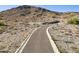 A long paved walkway leads to a rock wall with desert landscaping and hillside views at 3367 N Highlands Dr # 39, Buckeye, AZ 85396