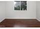 A bright, empty bedroom with hardwood floors and a large window providing natural light at 5976 W Alameda Rd, Glendale, AZ 85310