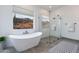 Bright bathroom featuring a modern soaking tub next to a large window with desert views and a glass walk-in shower at 6564 W Apex Ave, Queen Creek, AZ 85144