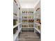 Organized walk-in pantry with white shelving stocked with a variety of dry goods and wooden floor at 6564 W Apex Ave, Queen Creek, AZ 85144