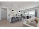 Open-concept kitchen with white cabinetry, island seating, and adjacent dining area with dark wood table at 6579 W Apex Ave, Queen Creek, AZ 85144