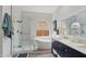 A bright bathroom features a glass shower, soaking tub, blue accent vanity, and white walls at 6901 W Tonto Dr, Glendale, AZ 85308
