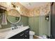 Charming powder room with floral wallpaper, a vanity, and a round mirror at 6901 W Tonto Dr, Glendale, AZ 85308