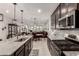 Modern kitchen with stainless steel appliances, granite countertops, dark cabinets, and open layout to the living area at 13384 W Red Range Way, Peoria, AZ 85383