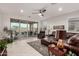 Spacious living room features a leather sofa, ceiling fan, and sliding glass doors to the outdoor patio at 13384 W Red Range Way, Peoria, AZ 85383