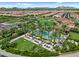 Aerial view of the community pool area with lounge chairs, umbrellas, palm trees, and a beautiful grassy area at 1588 E Sweet Citrus Dr, Queen Creek, AZ 85140