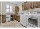 Laundry room with wood cabinets, counter space, sink, mini fridge, and modern washer and dryer units at 1588 E Sweet Citrus Dr, Queen Creek, AZ 85140