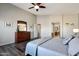 Comfortable main bedroom featuring a ceiling fan, wood floors, and a peek into the primary ensuite at 17514 W Desert Sage Dr, Goodyear, AZ 85338