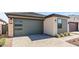 A modern home featuring a gray garage door and neutral stucco and siding, complemented by a brick driveway at 20332 W Sells Dr, Buckeye, AZ 85396