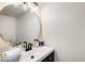 Stylish half bathroom featuring a round mirror, black fixtures, and classic white sink at 5350 N 3Rd Ave, Phoenix, AZ 85013