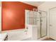 Bathroom showcasing a soaking tub and glass-enclosed shower with an orange accent wall at 5423 W Range Mule Dr, Phoenix, AZ 85083