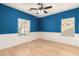 Well-lit bedroom with blue walls, white trim, hardwood floors and a ceiling fan at 5423 W Range Mule Dr, Phoenix, AZ 85083
