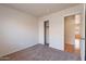 Neutral bedroom showcasing carpeted flooring, a sliding door closet, and an adjoining room with wood flooring at 8010 W Adam Ave, Peoria, AZ 85382