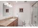Bright bathroom showcasing a granite countertop vanity, tile floors and a glass-enclosed shower-tub combination at 8220 E Crestwood Way, Scottsdale, AZ 85250