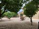 Backyard featuring gravel landscaping, mature trees, patio, and privacy wall at 13031 W Surrey Ave, El Mirage, AZ 85335