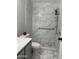 Renovated bathroom boasts marble-style tiled shower, modern fixtures, and accessibility features for comfort and style at 13031 W Surrey Ave, El Mirage, AZ 85335