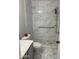 Updated bathroom featuring marble-look tiling, walk-in shower, and grab bars for added safety and convenience at 13031 W Surrey Ave, El Mirage, AZ 85335