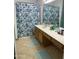 This bathroom boasts a floral shower curtain, a long countertop, and dual floor mats at 13031 W Surrey Ave, El Mirage, AZ 85335